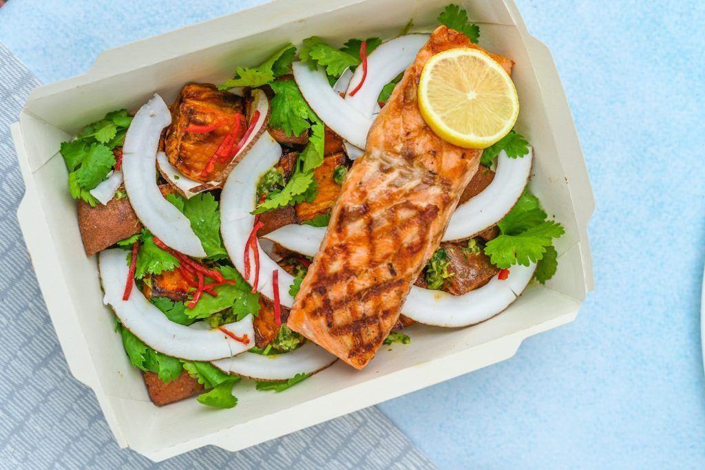 A tray of food with a piece of salmon and a lemon slice.