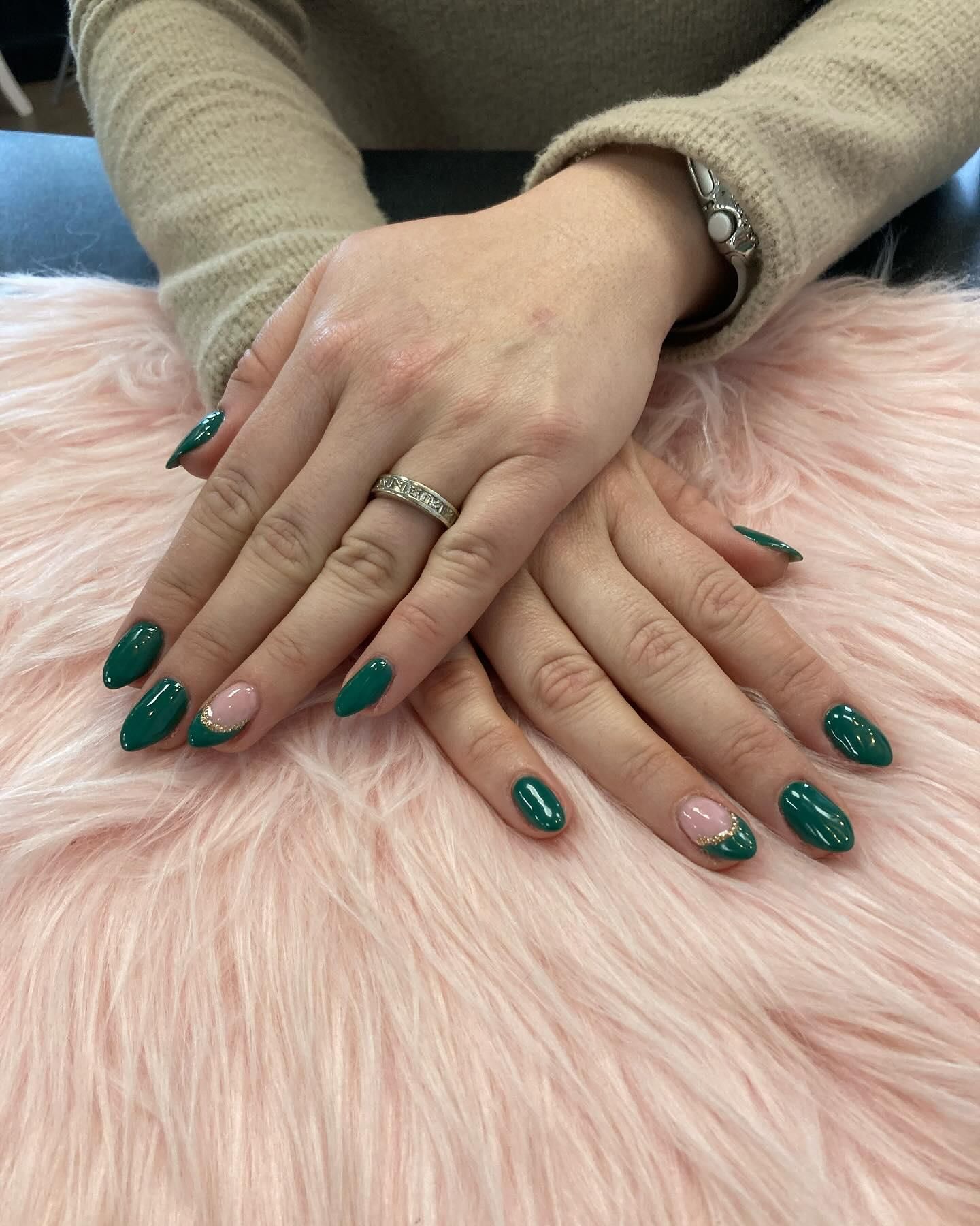 Hands with emerald green and pink crescent moon nail polish, resting on pink fur.