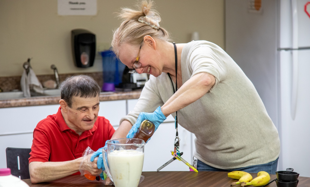 A woman is pouring milk into a pitcher for a man.