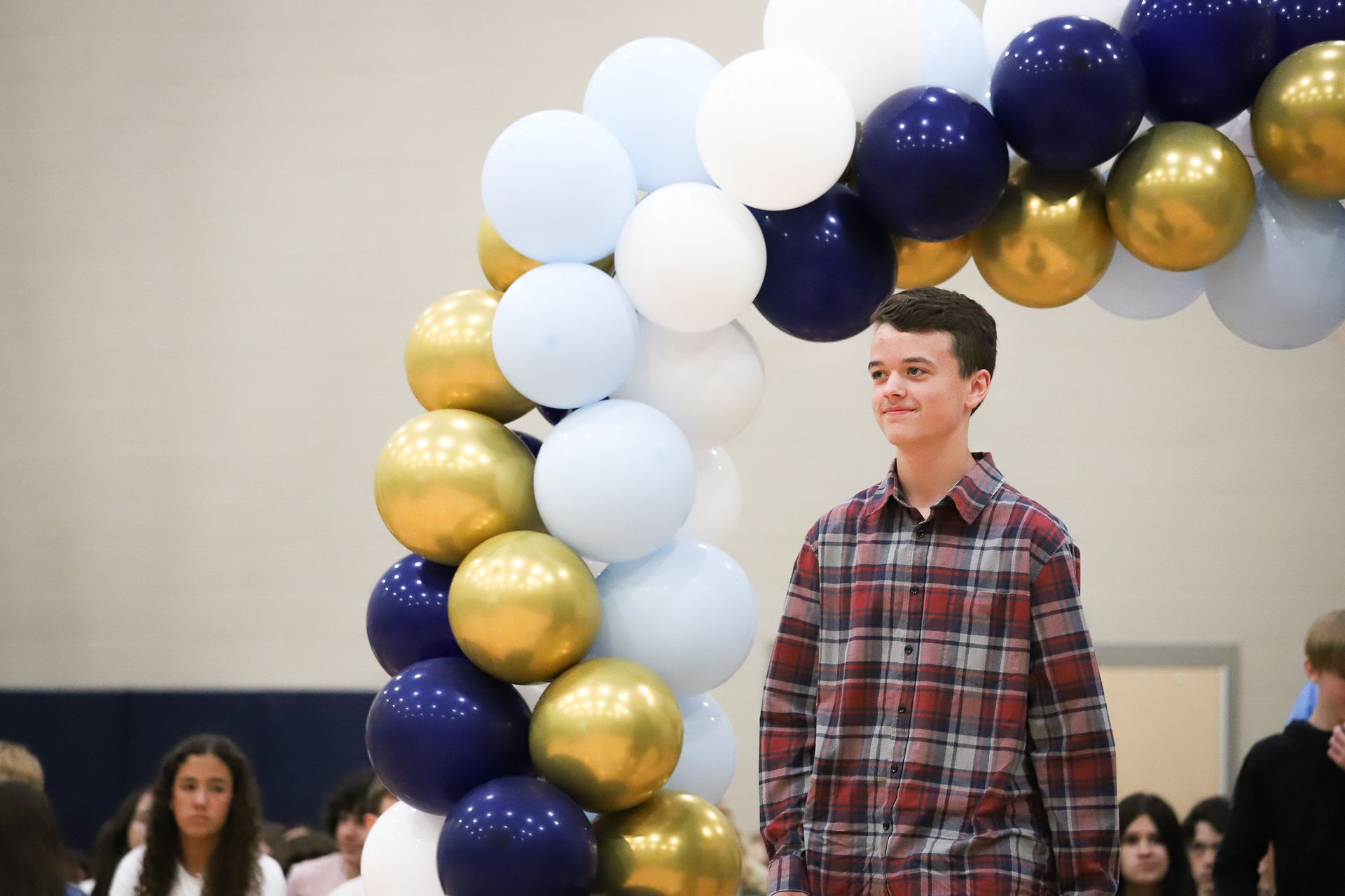 A young man is standing in front of a balloon arch.