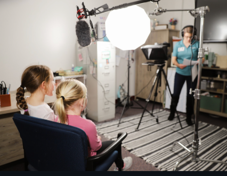 Two girls are sitting in front of a microphone in a room