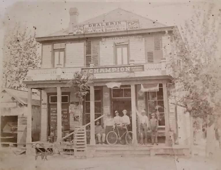 A group of men are standing on the porch of an old building.