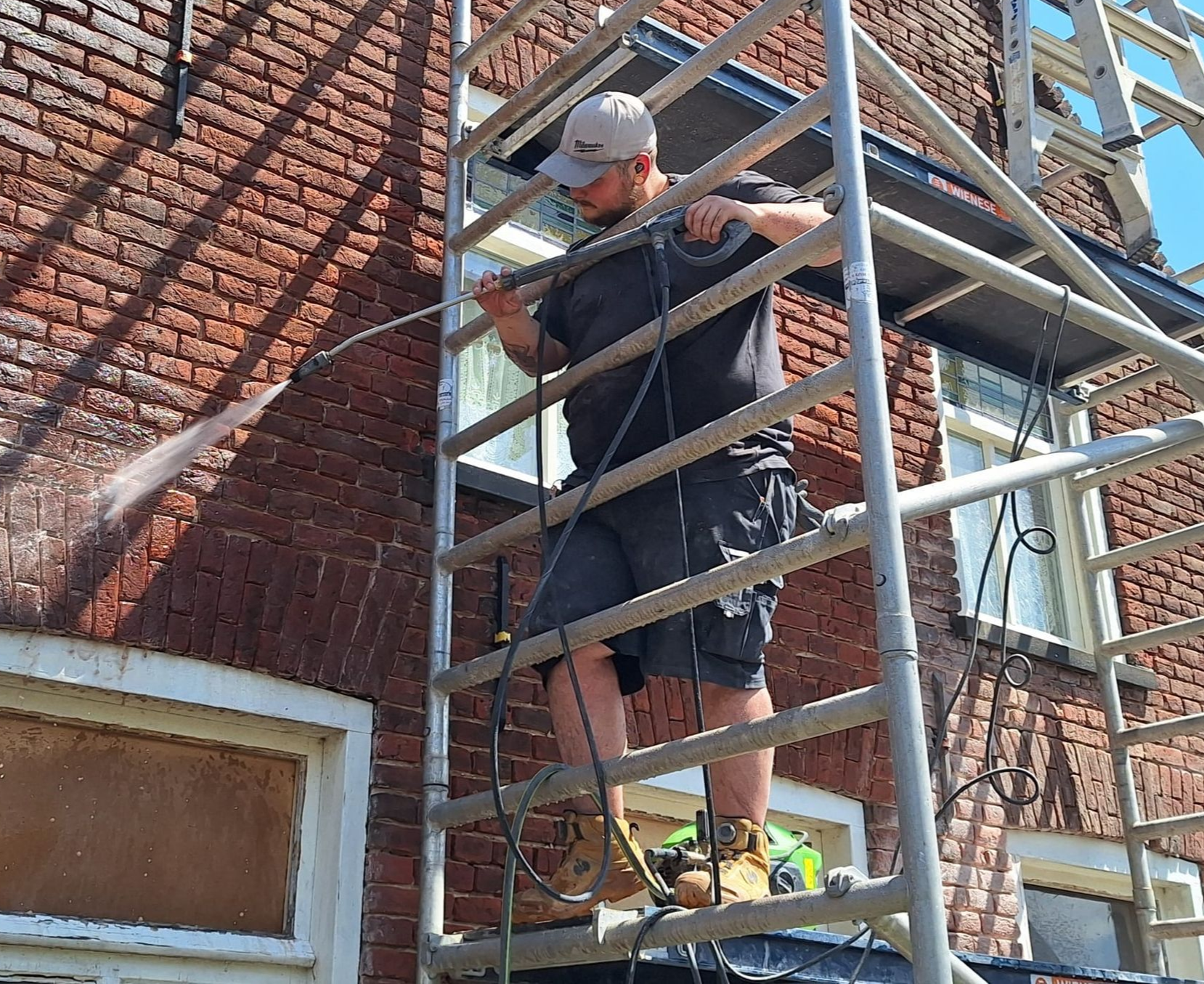 vakman die een gevel aan het reinigen is