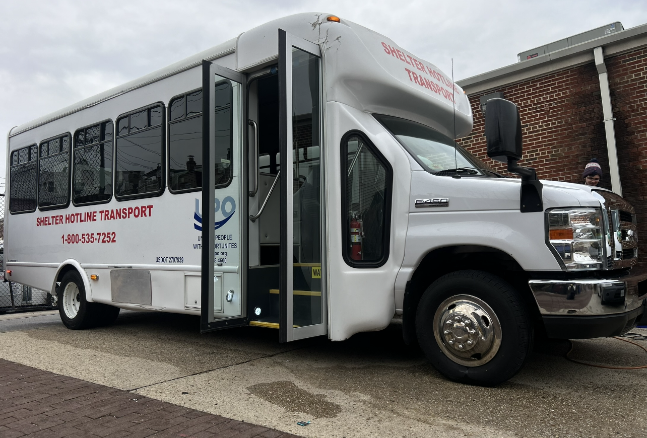 Ford E-450 shuttle bus parked curbside with passenger door open, showing exterior condition before professional bus detailing