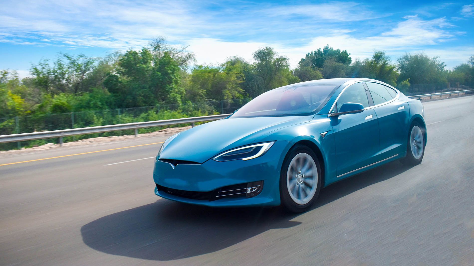 blue Tesla car driving down road
