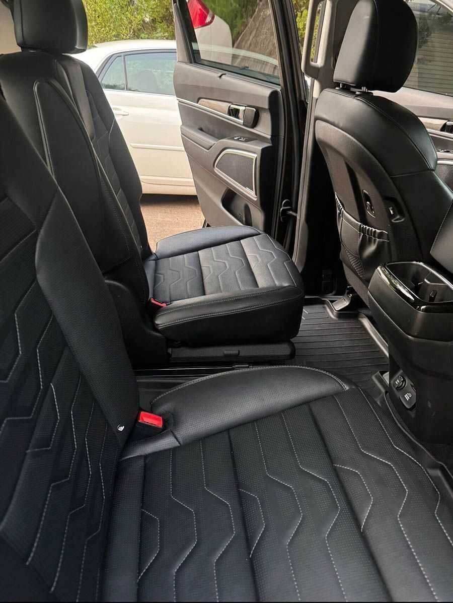 Car's rear interior with black leather seats, one folded forward, revealing the floor for a comprehensive bio-cleaning.