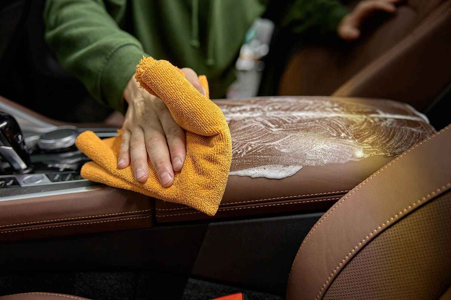 Technician cleaning interior surfaces with microfiber towel during car mold remediation service.
