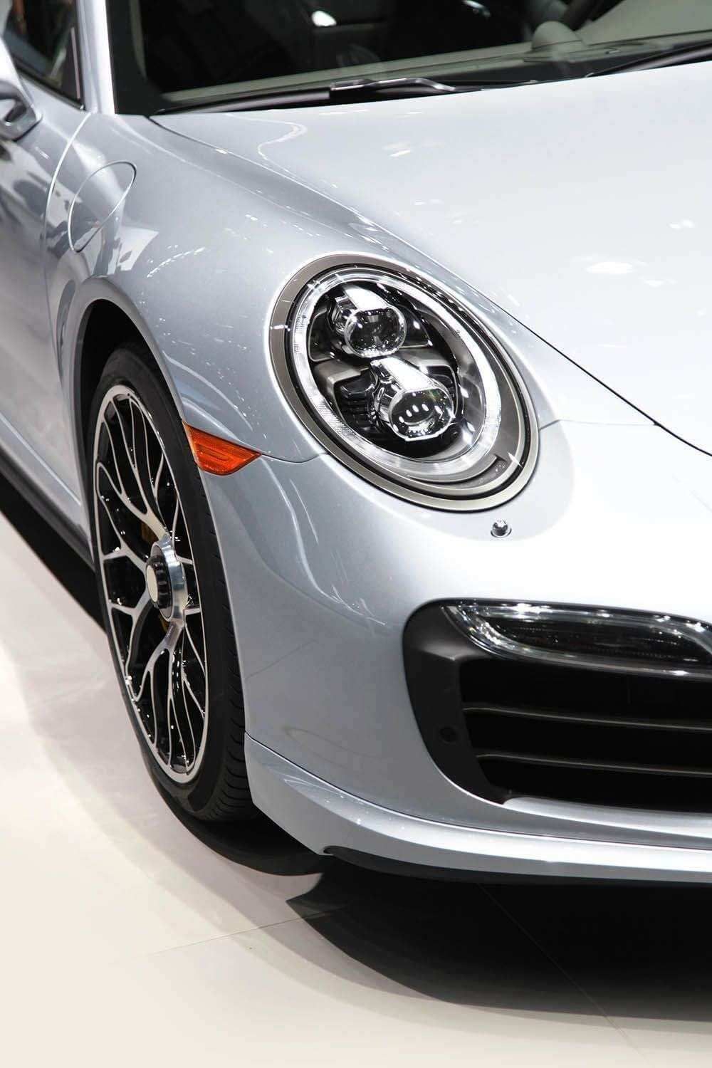 Meticulously detailed silver Porsche 911 front quarter, showcasing its gleaming paint, headlight, and intricate wheel.