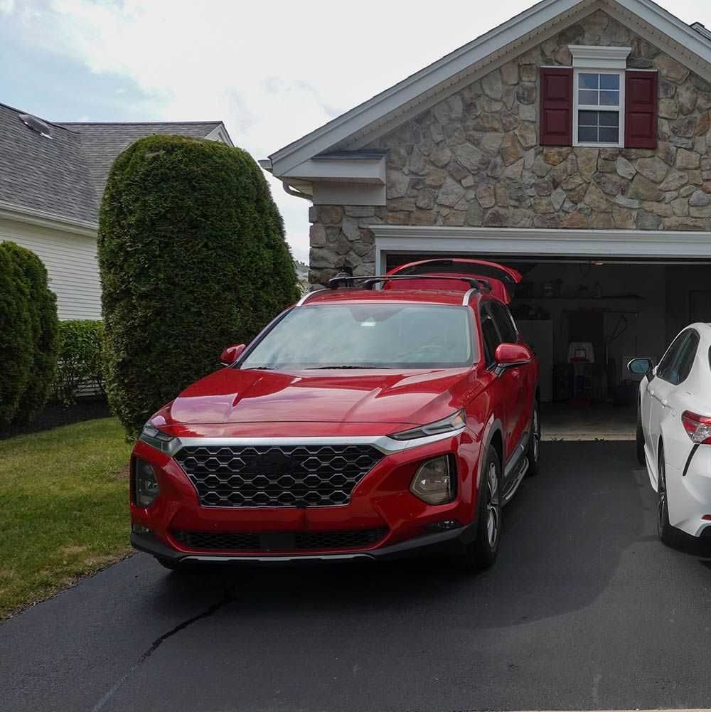 Red SUV undergoing driveway detail service with doors and hatch open.