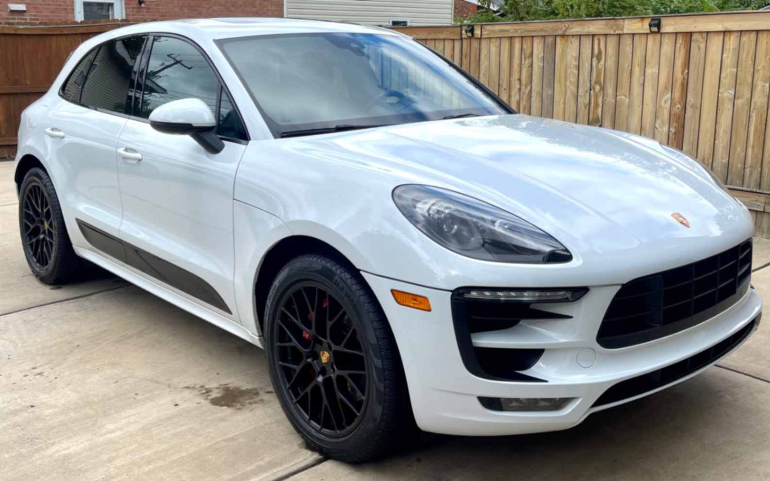 Porsche Macan parked near a building, featuring sharp aerodynamic lines, black wheels.