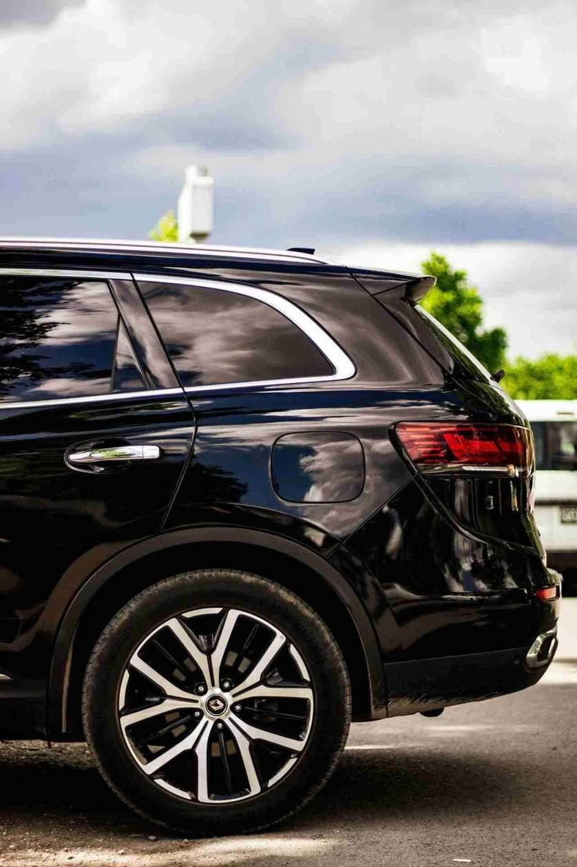 Black SUV side panel perfectly reflecting a cloudy sky, demonstrating professional detailing.