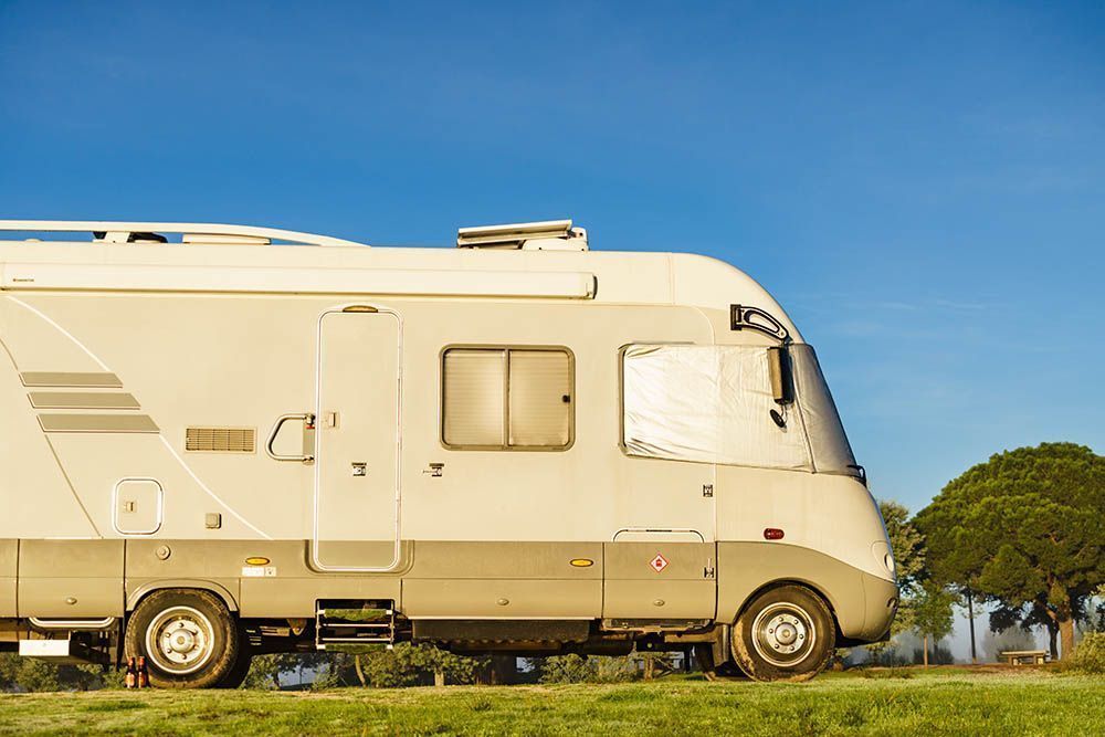 Class C motorhome staged for full exterior detailing under direct sunlight.