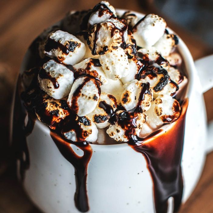 a cup of hot chocolate with marshmallows and chocolate sauce .