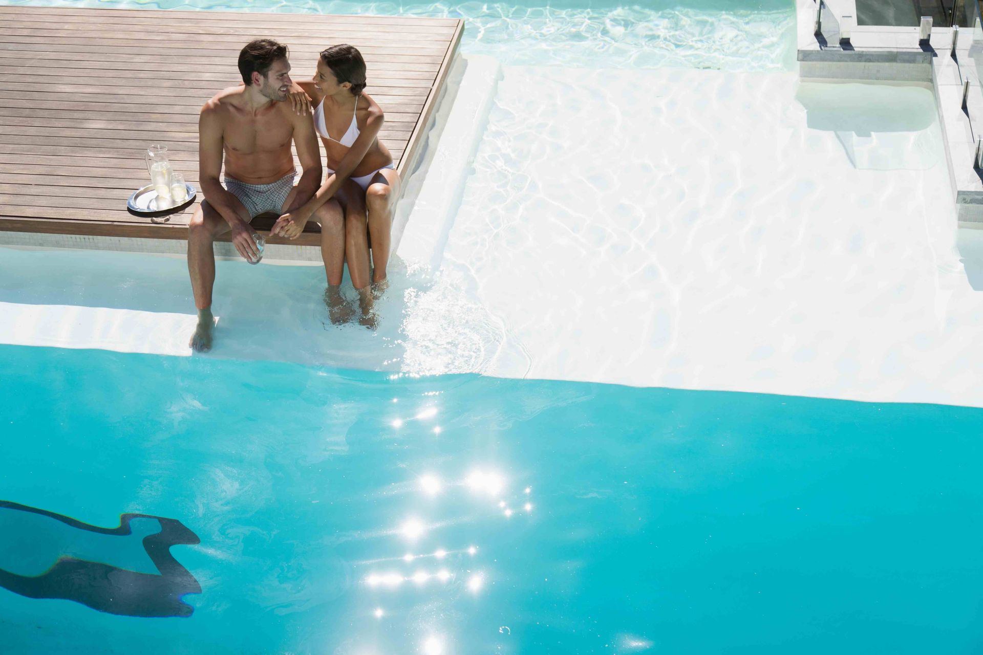 A couple embracing on the edge of a custom swimming pool deck