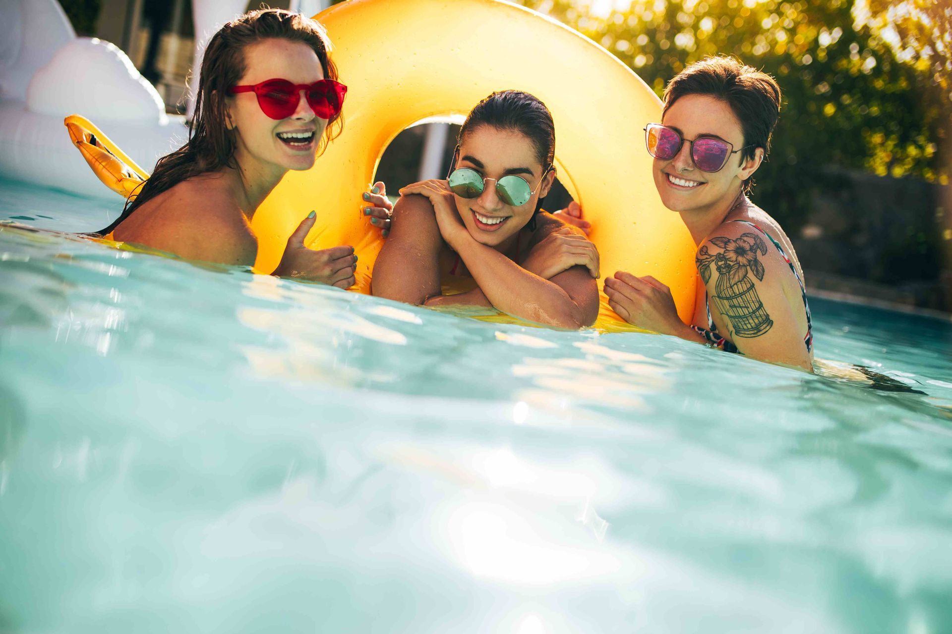 Three girls having a great time in their pool outside, smiling