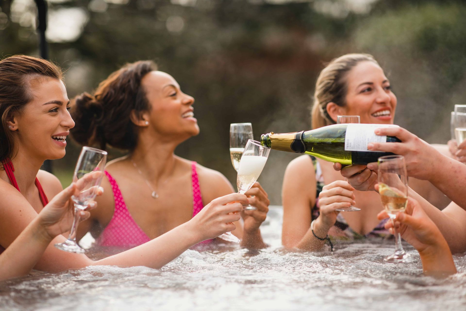 Friends drinking champagne in their new hot tub