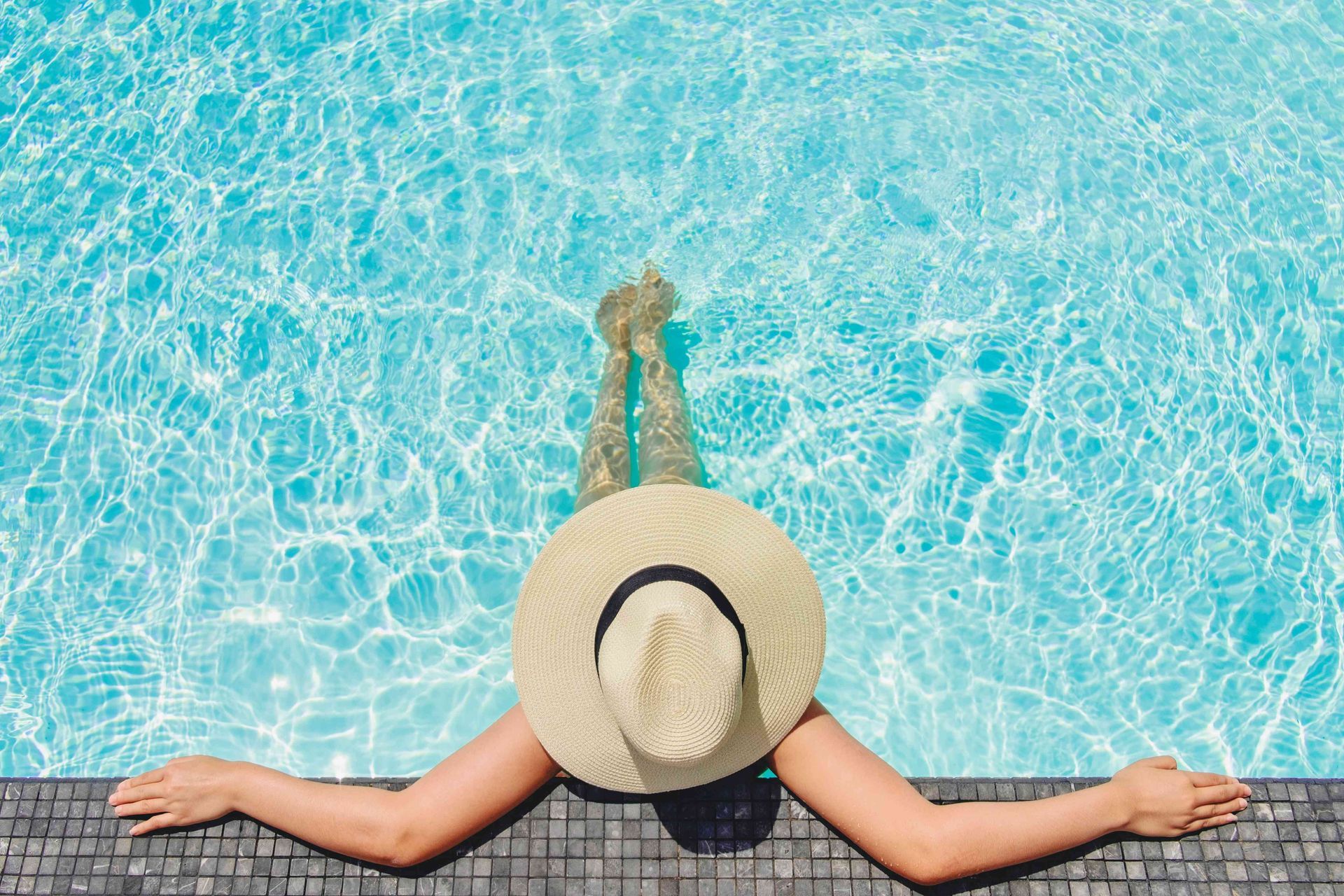 A woman relaxing in a pool with a hat on
