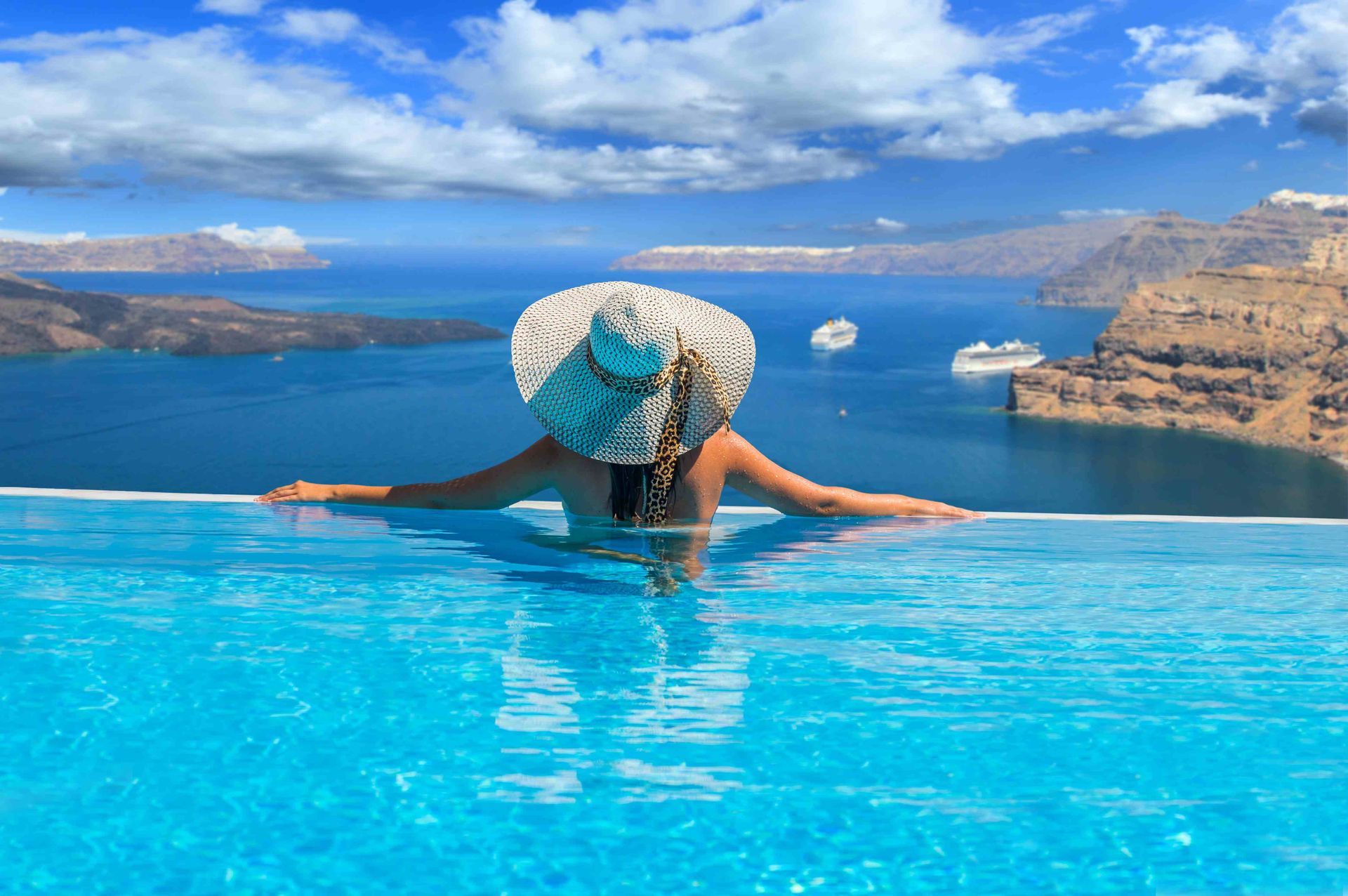 A woman with a sunhat at the edge of an infinity pool