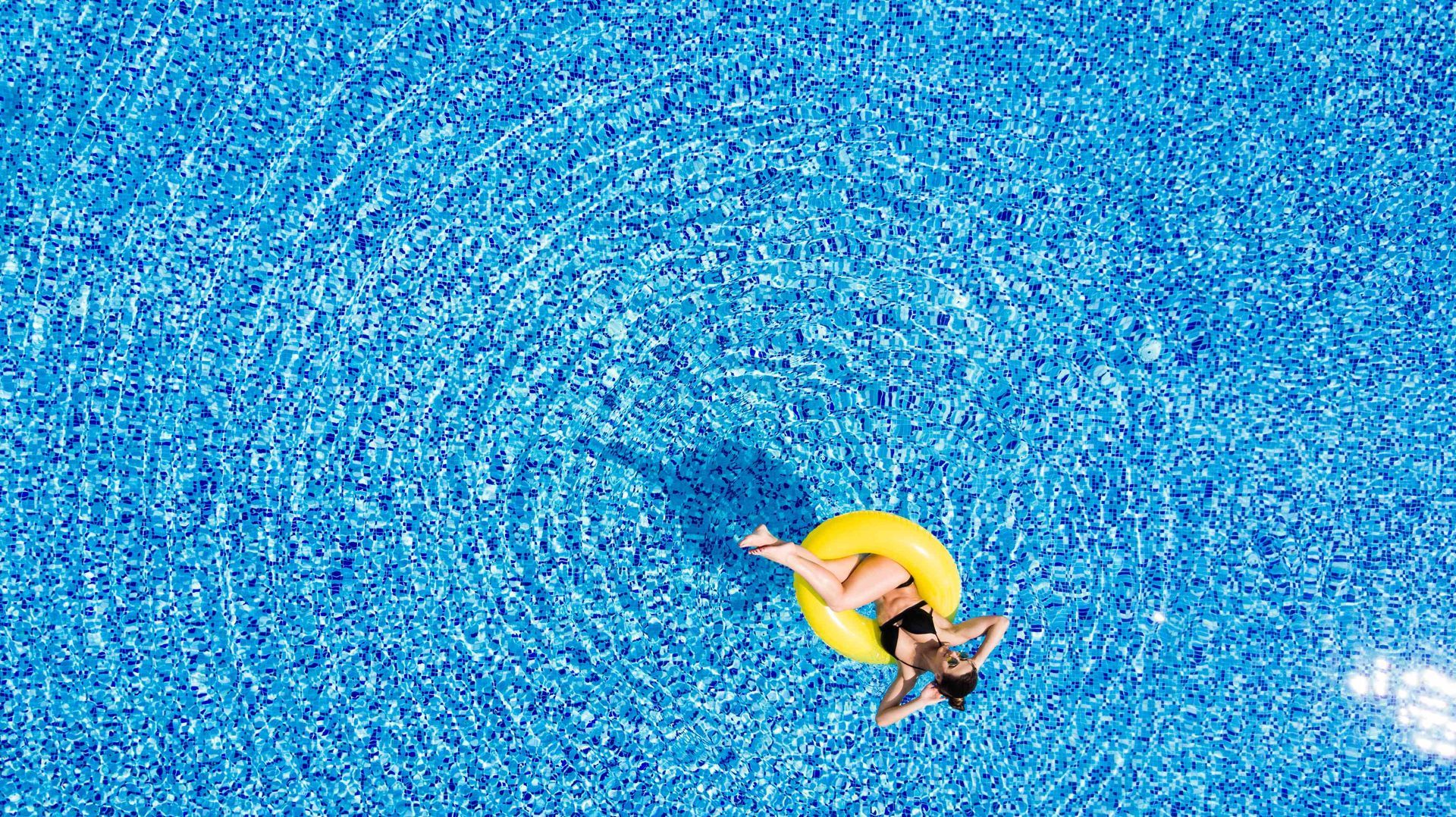 A woman on a yellow intertube floating in a pool