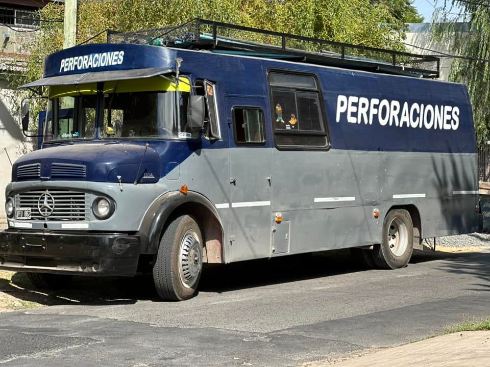 Una camioneta azul y gris con cartel que dice perforaciones escritas en el costado.