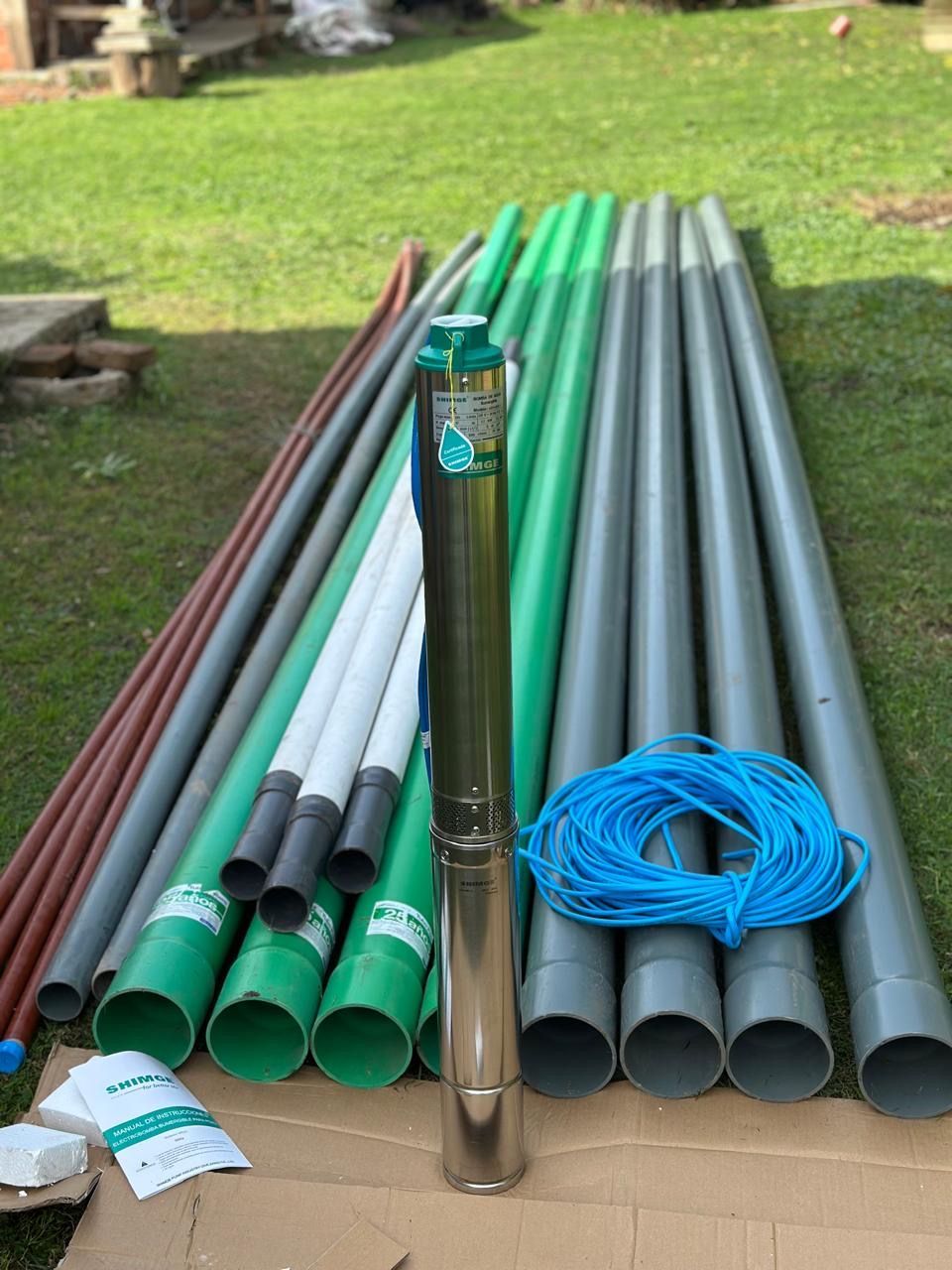 Una pila de tuberías y una bomba están colocadas encima de una caja de cartón.