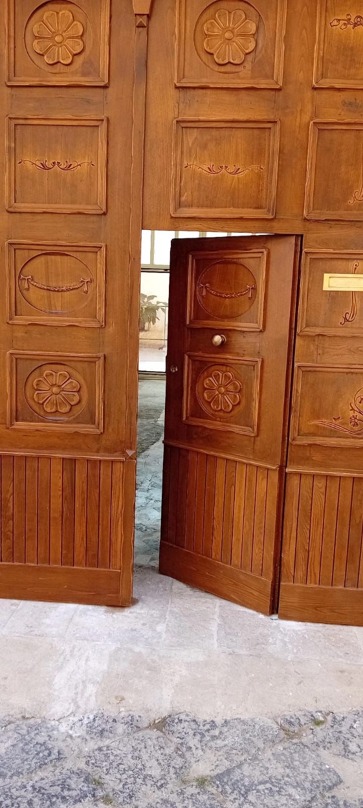 Una porta di legno con un disegno floreale è aperta.