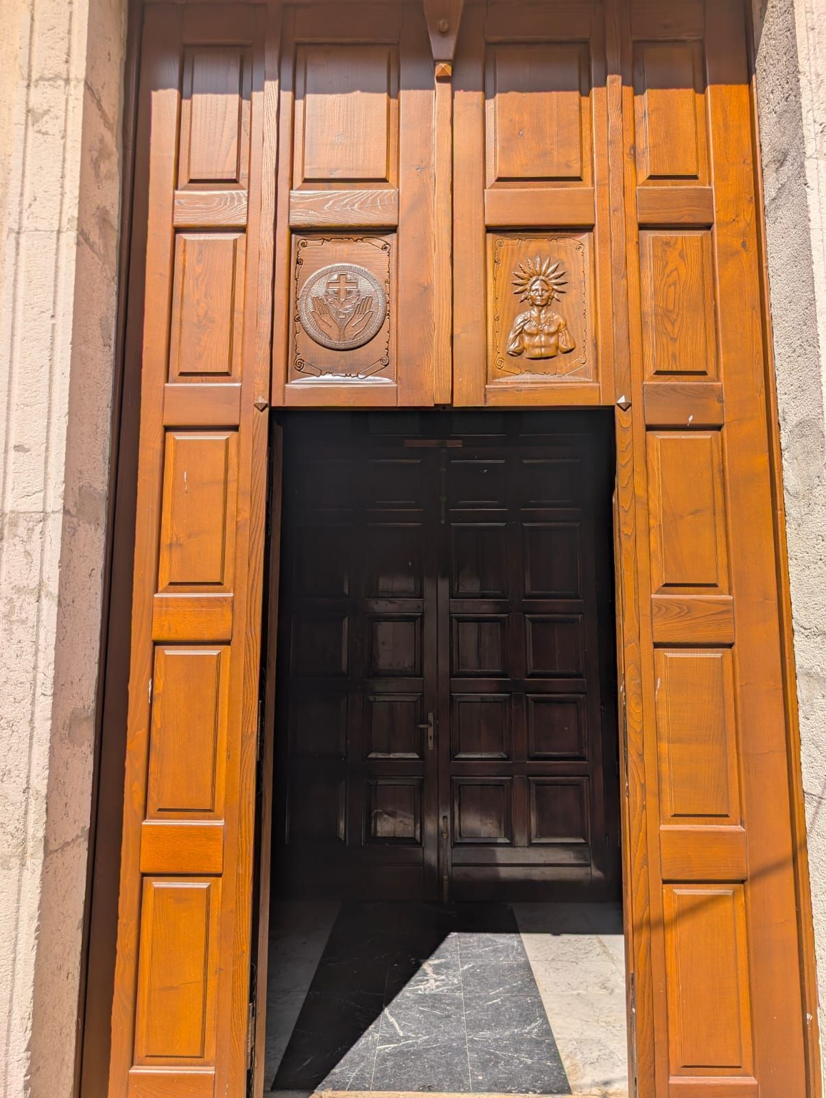 Una grande porta di legno è aperta su una stanza buia
