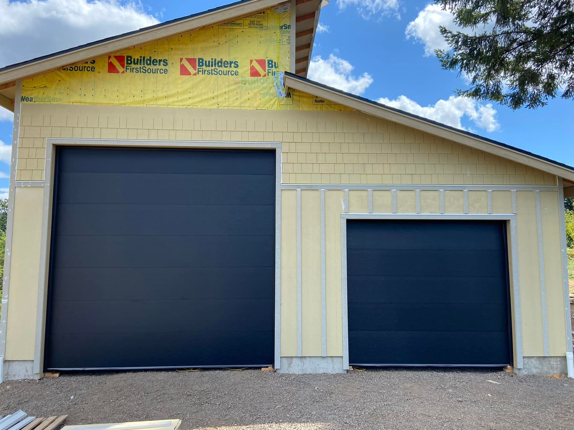 A garage with two black garage doors is under construction.