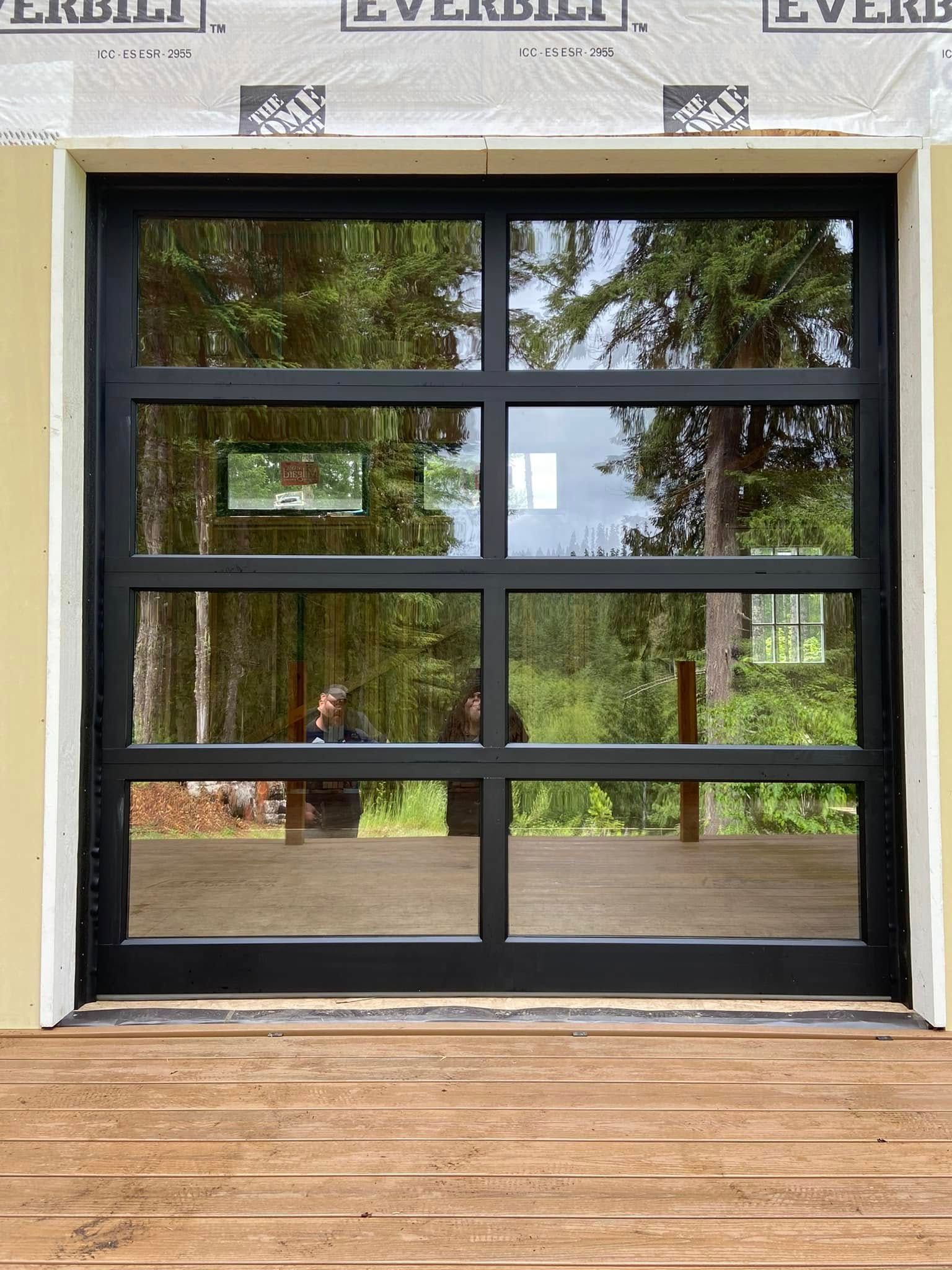 A black garage door with a lot of windows is sitting on top of a wooden deck.