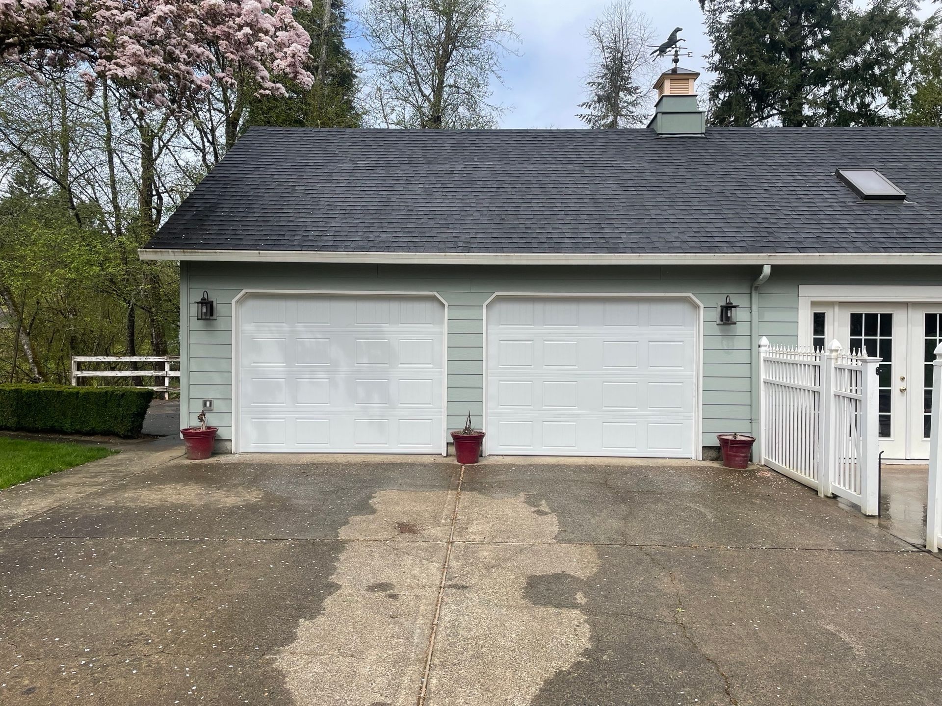 A garage with two white garage doors and a black roof