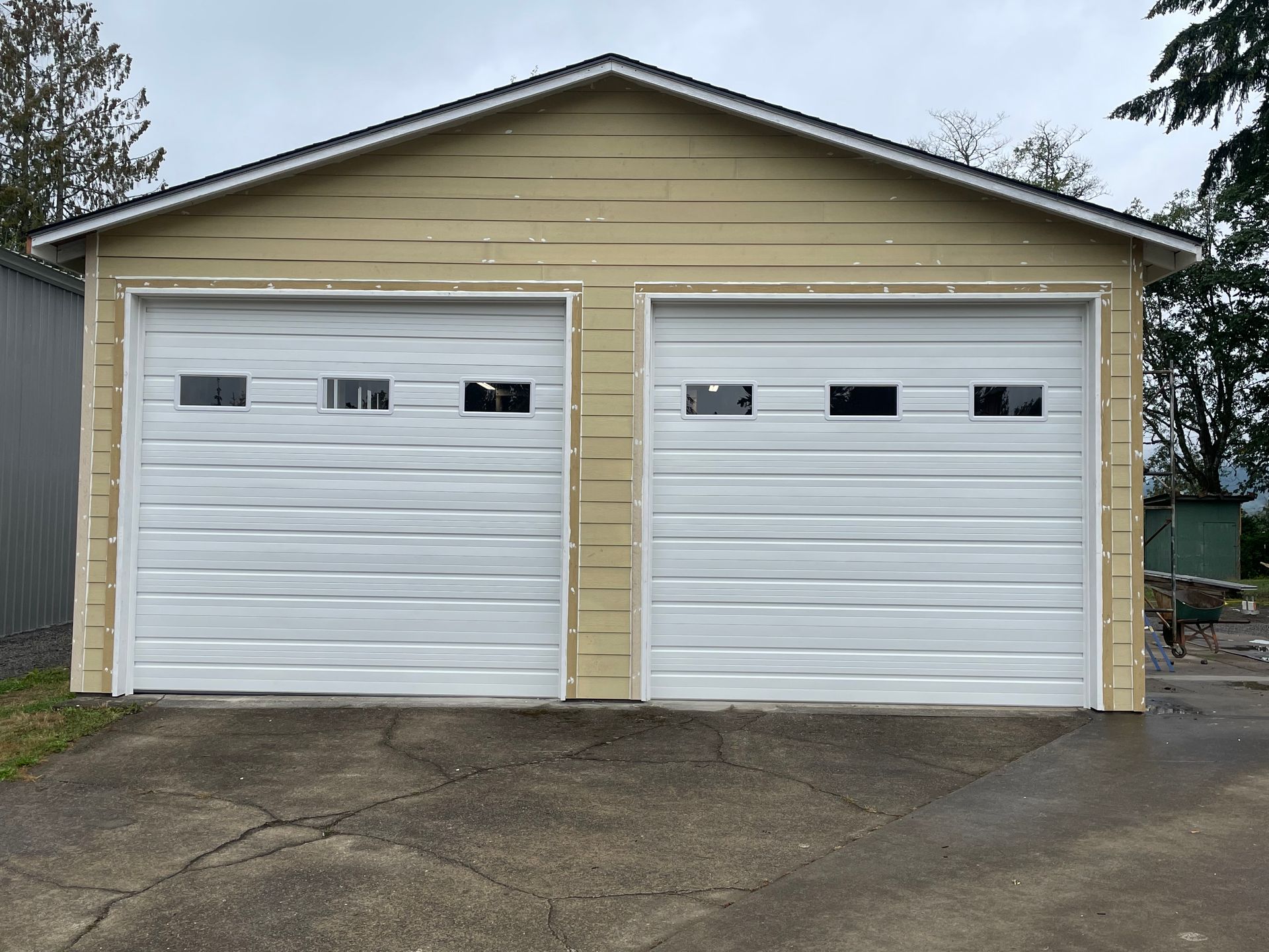 A garage with two white garage doors and a yellow siding.