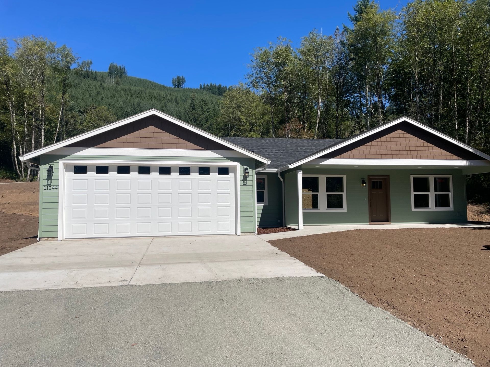 A green and brown house with a white garage door
