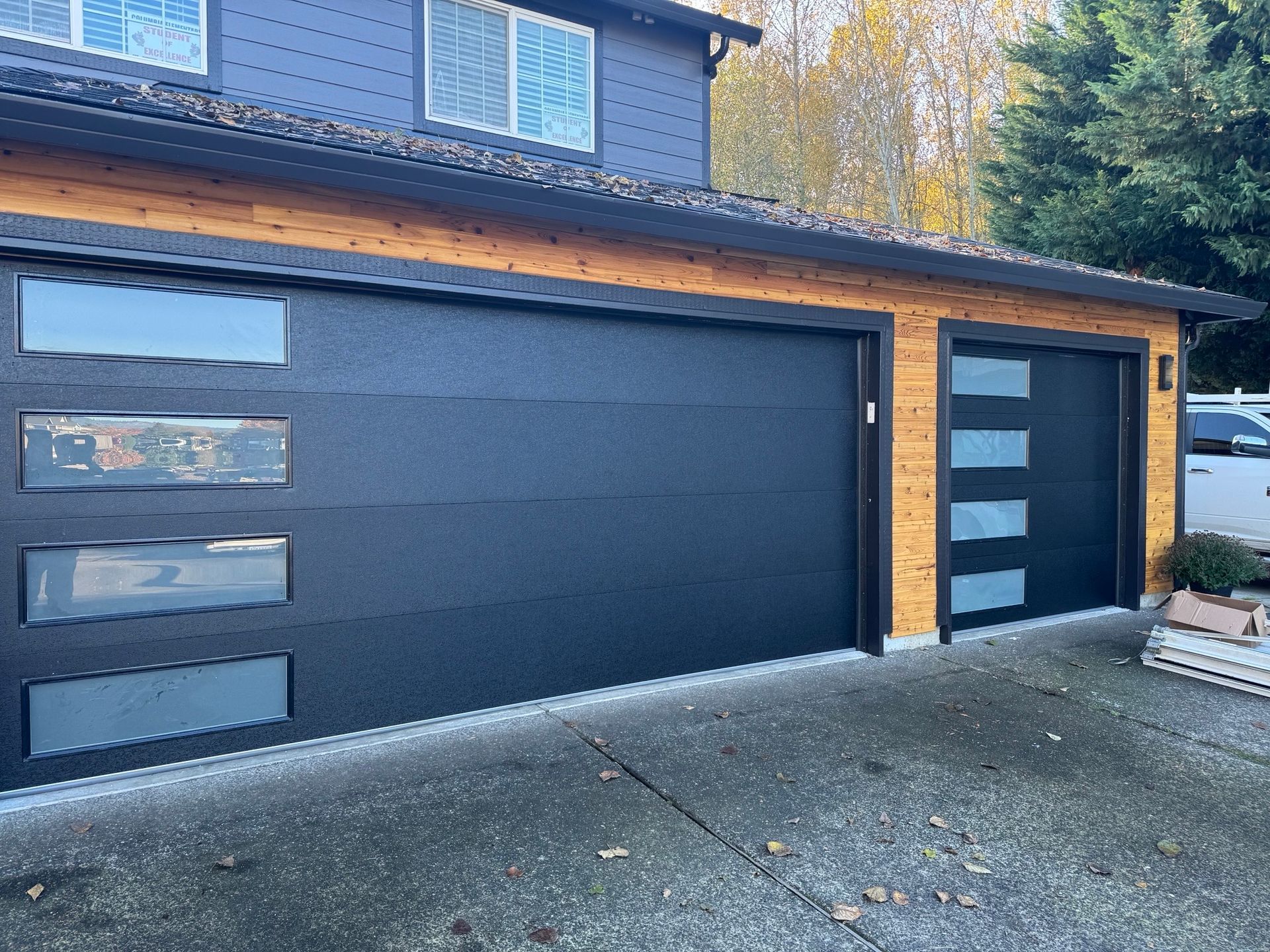 A black garage door is sitting in front of a blue house.