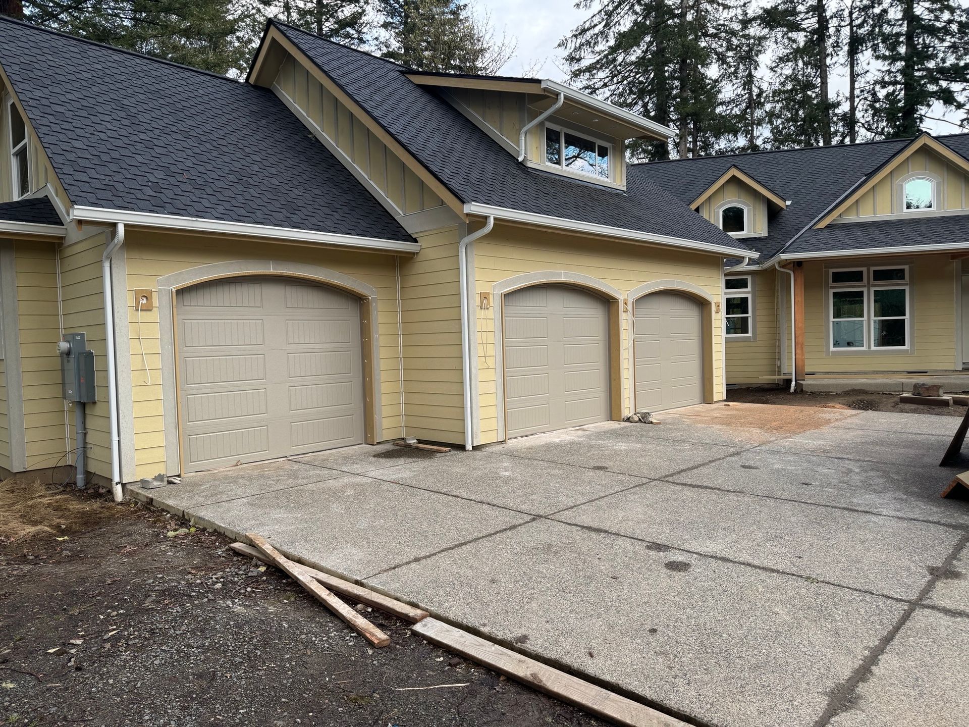 A yellow house with three garage doors and a blue roof