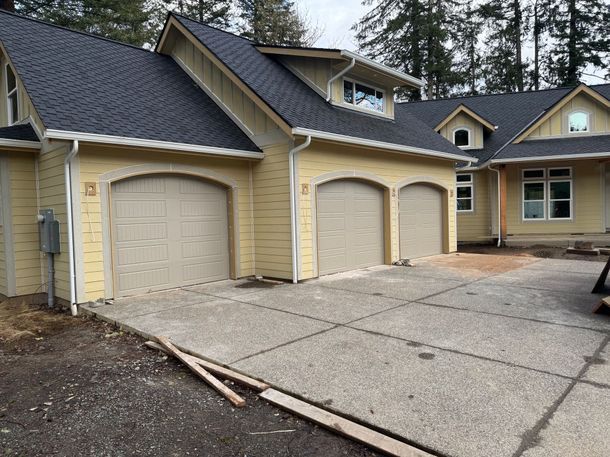 A yellow house with three garage doors and a blue roof