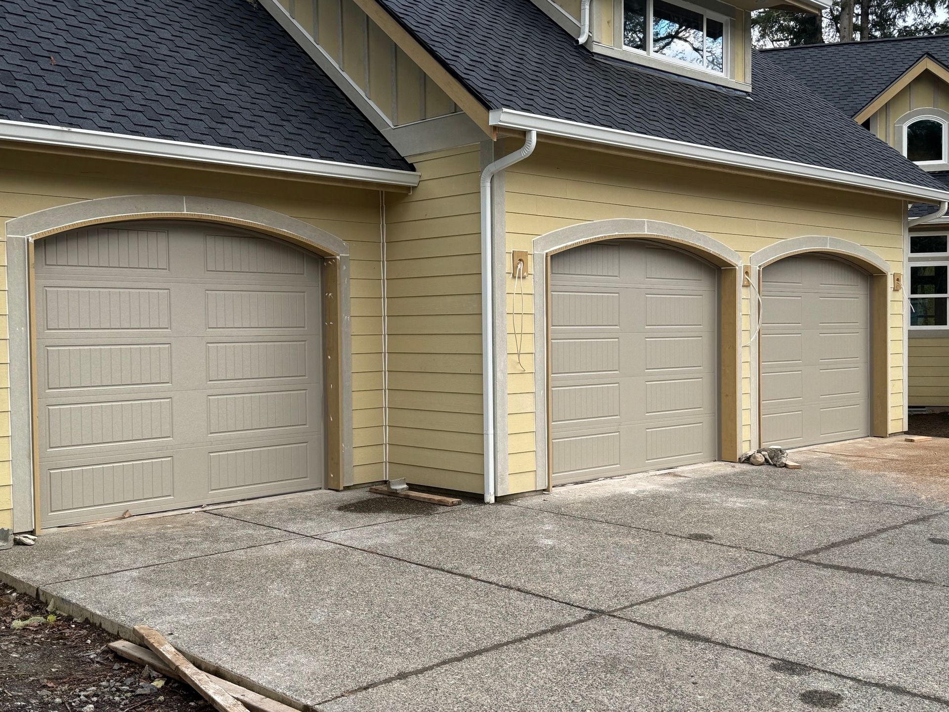 There are three garage doors on the side of a house.