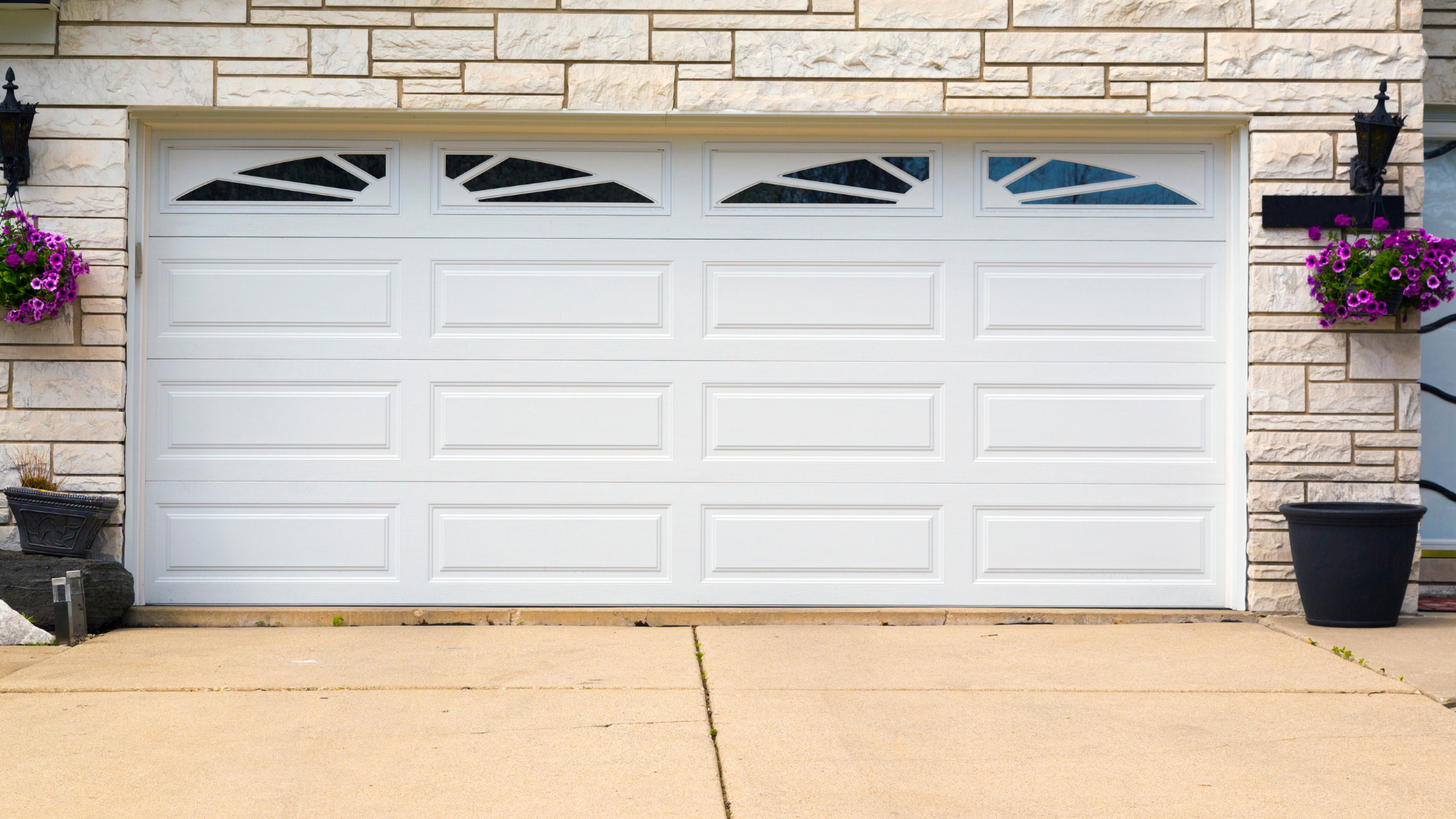 A white garage door is sitting in front of a brick building.