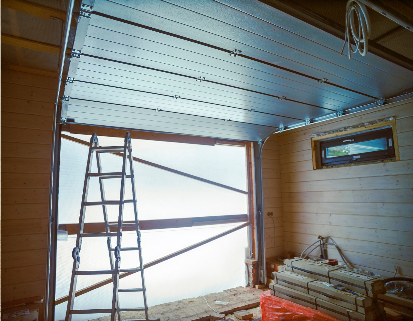 A ladder is sitting in a garage next to a garage door.