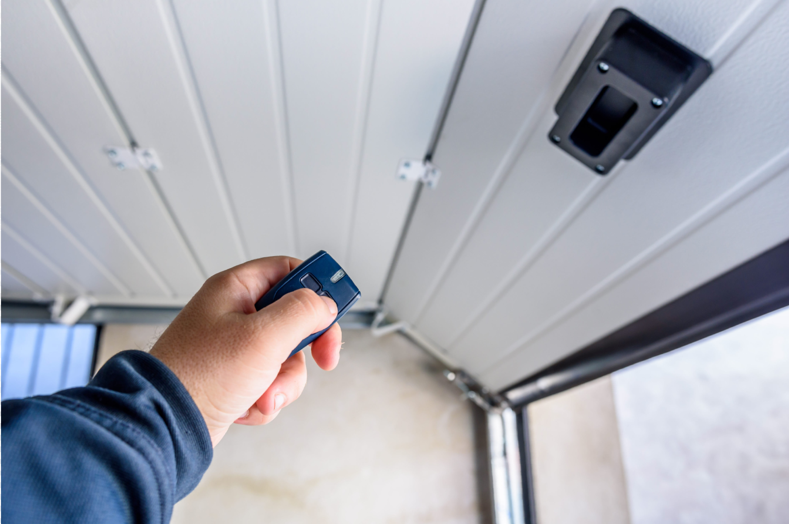 A person is using a remote control to open a garage door.