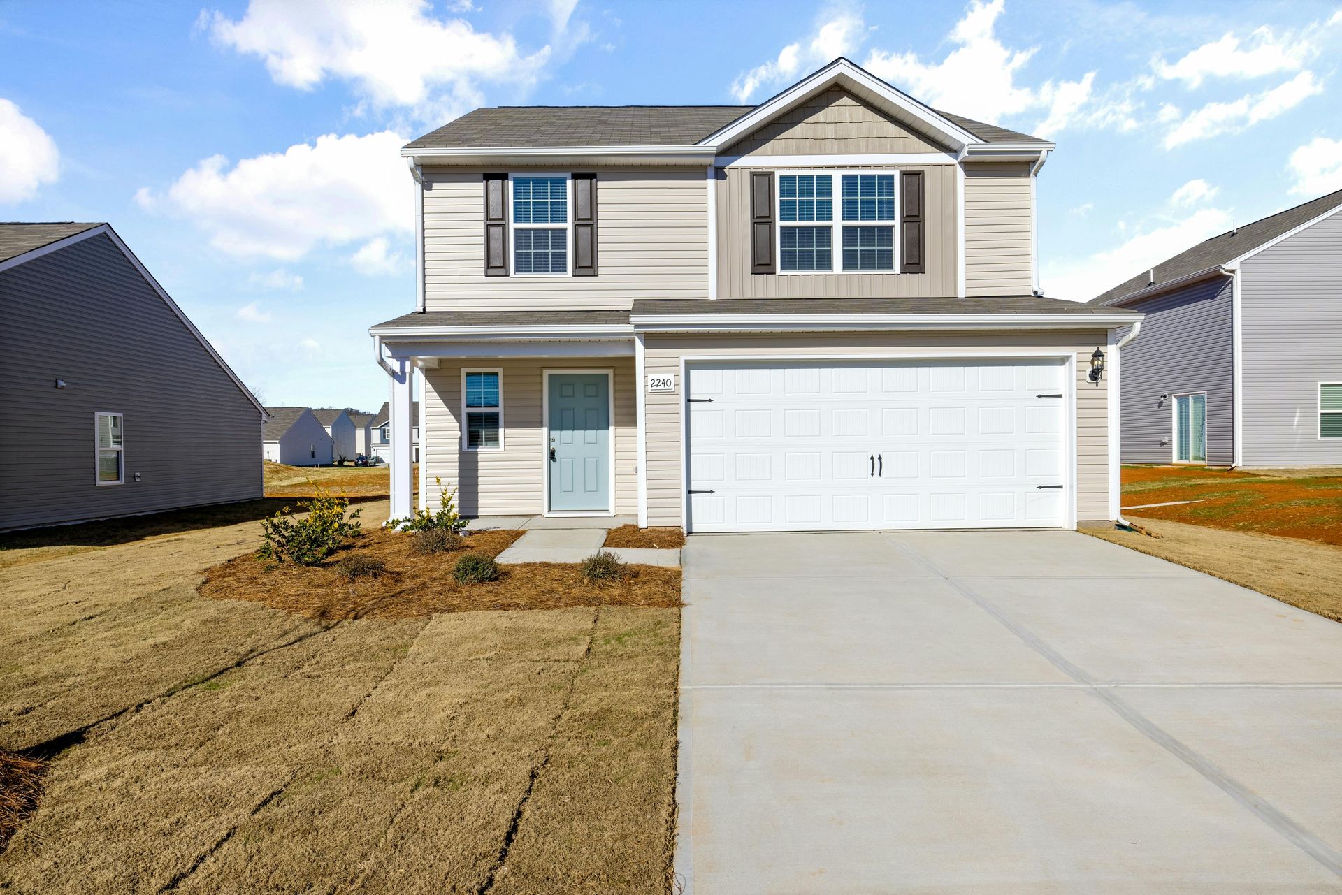 The front of a house with a white garage door and a concrete driveway.