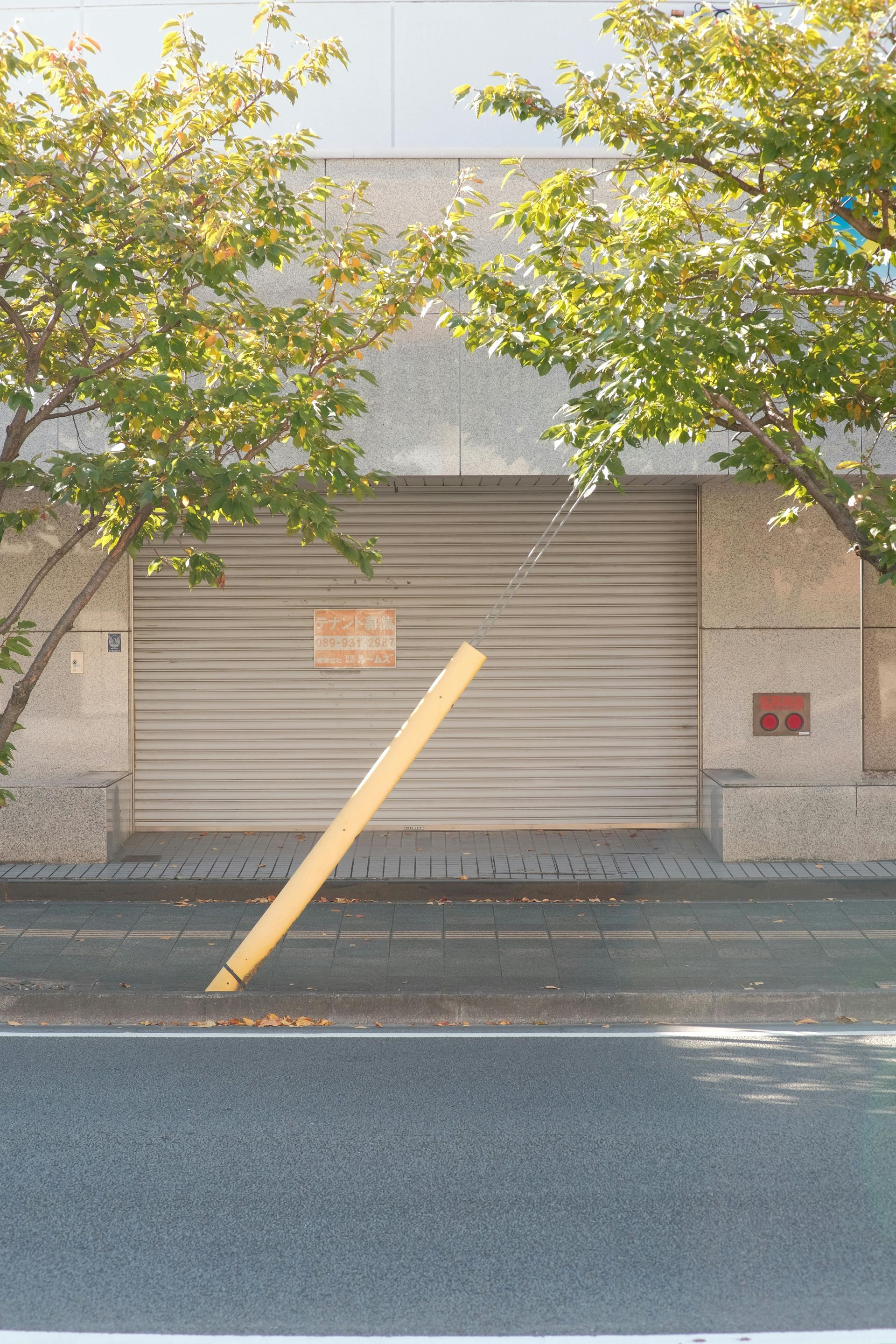 A yellow pole is leaning against a building on the side of the road.