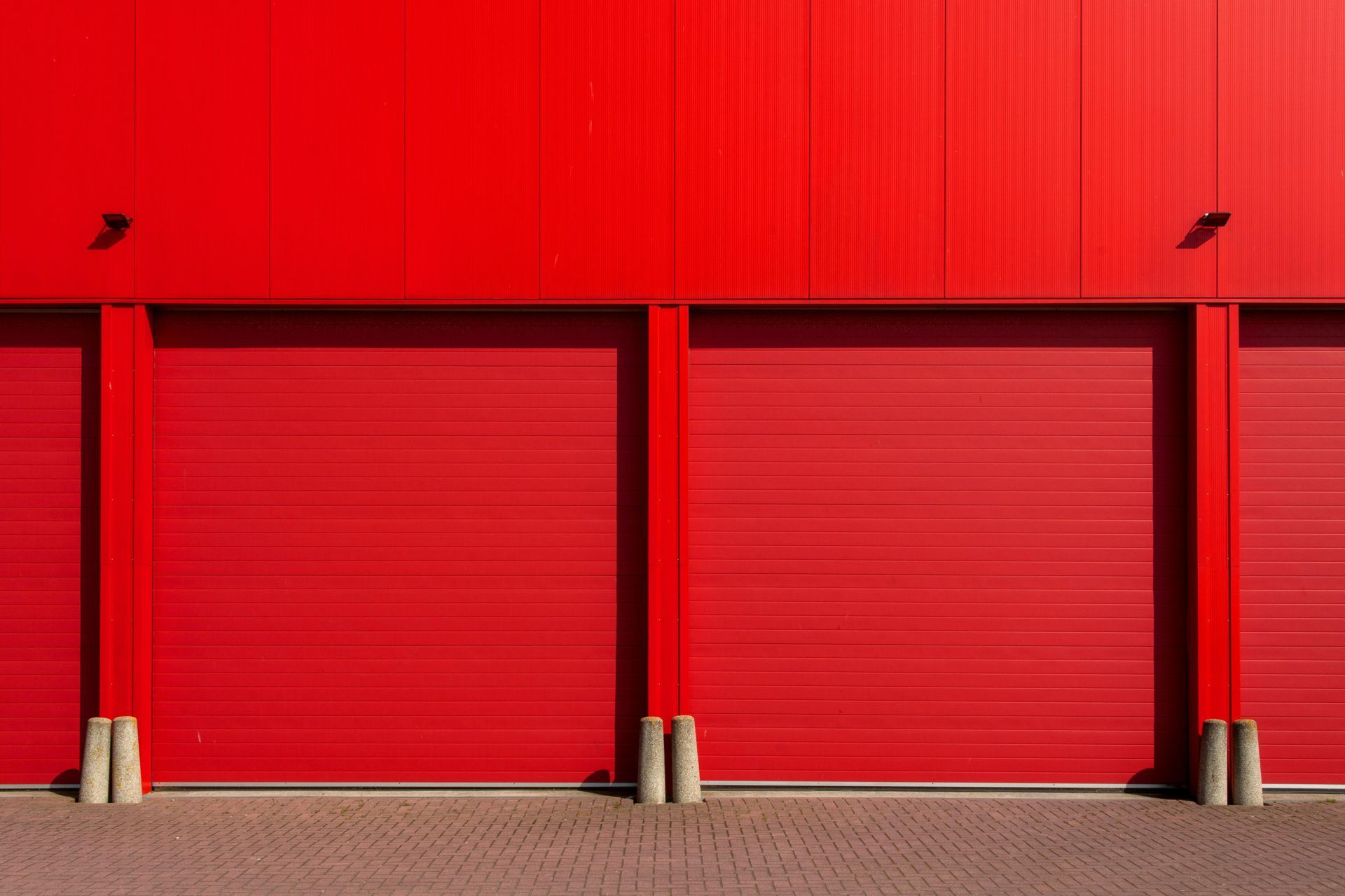 Red building exterior with three garage doors.