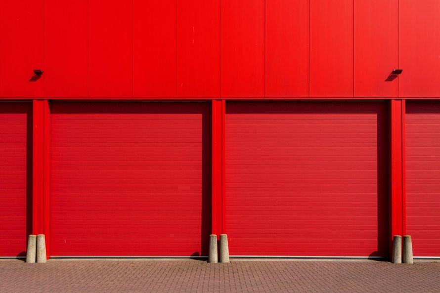 A row of red garage doors on a red building.