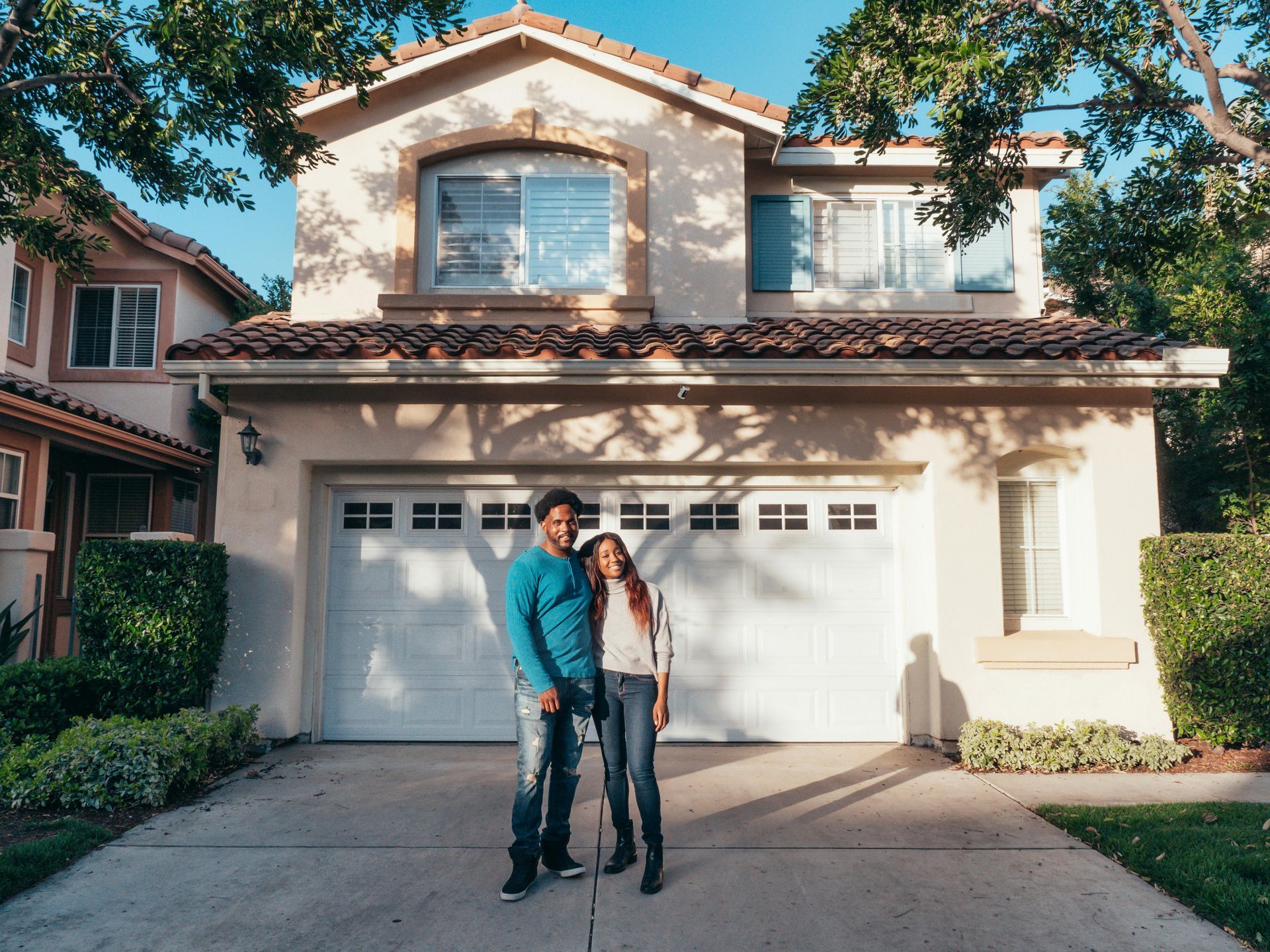 A man and a woman are standing in front of a house.
