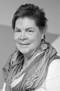 Smiling older woman wearing a scarf and earrings. Studio shot with light background.