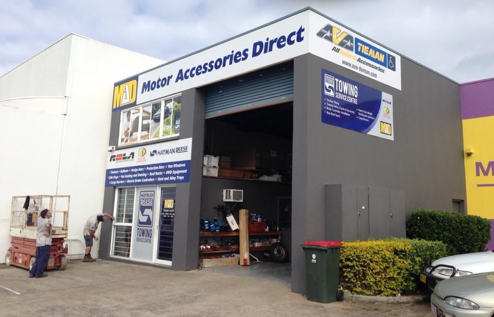 Motor Accessories Direct Storefront With Open Garage Door, Signs, and People Outside — Motor Accessories Direct In Tweed Heads, NSW