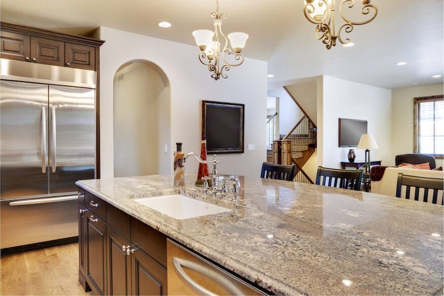 Large open kitchen with dark wood cabinets and light colored granite countertop