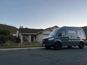 White work van parked on a quiet street in front of a house at dusk