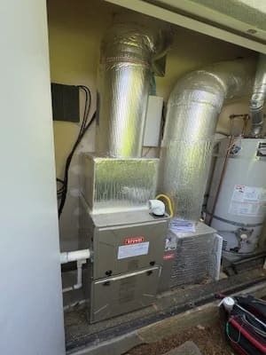 Industrial HVAC furnace with silver ductwork and a gray unit in a utility room