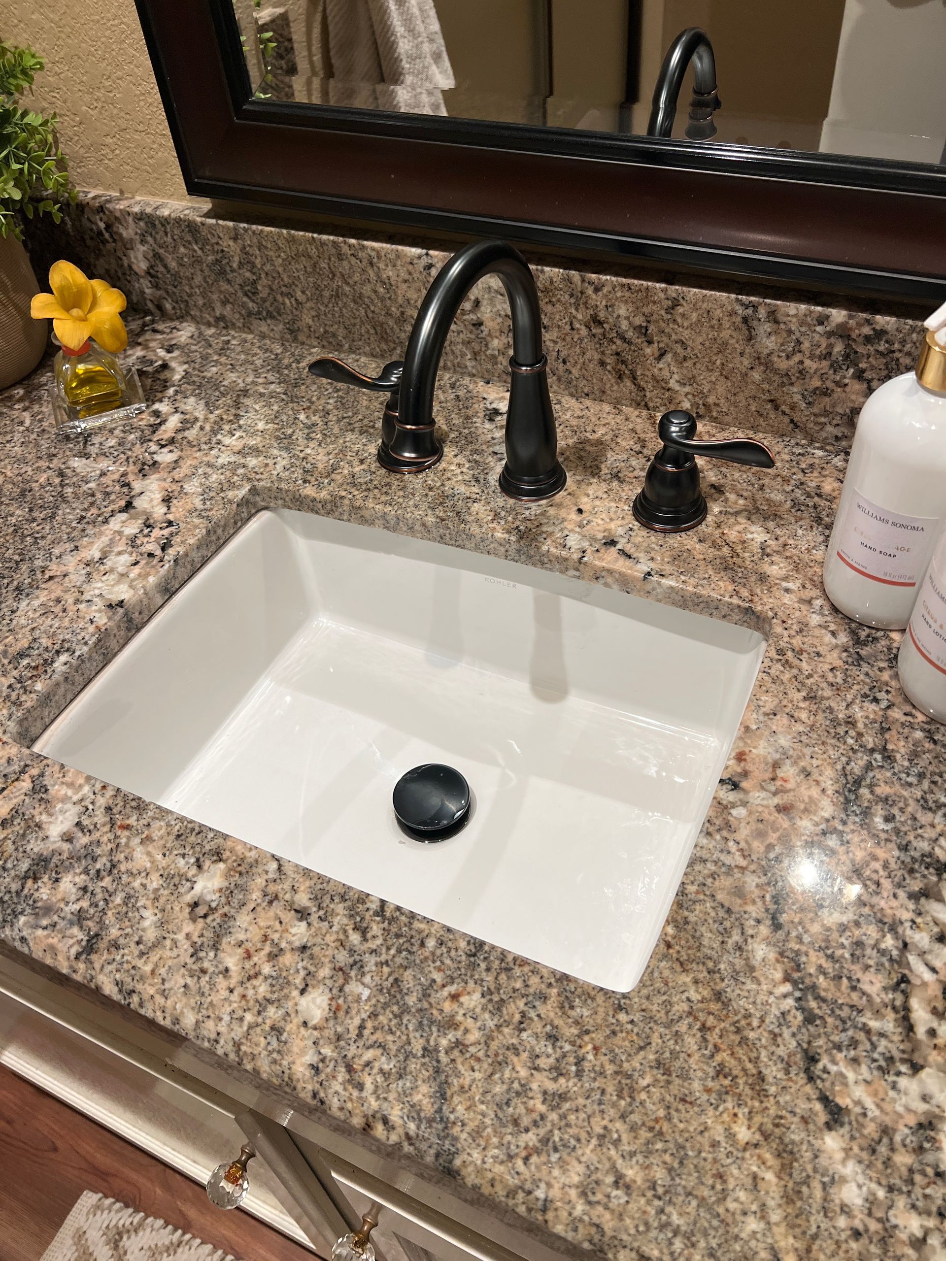 Bathroom vanity with granite countertop, white square sink, dark faucet, mirror, and soap dispenser